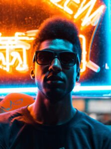 Siga as regras do algoritmo : Influenciador nas ruas &agrave; noite com backlight azul e laranja ao fundo