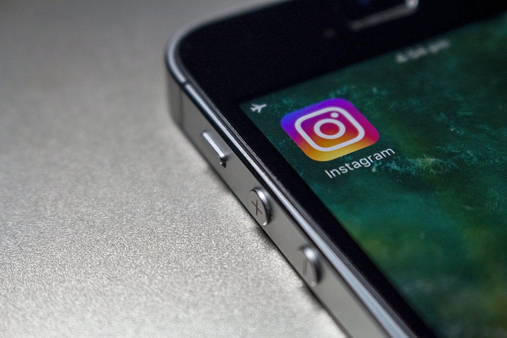 O que &eacute; o Instagram? : &Iacute;cone do instagram aparecendo em uma tela de um celular sob um plano acinzetado