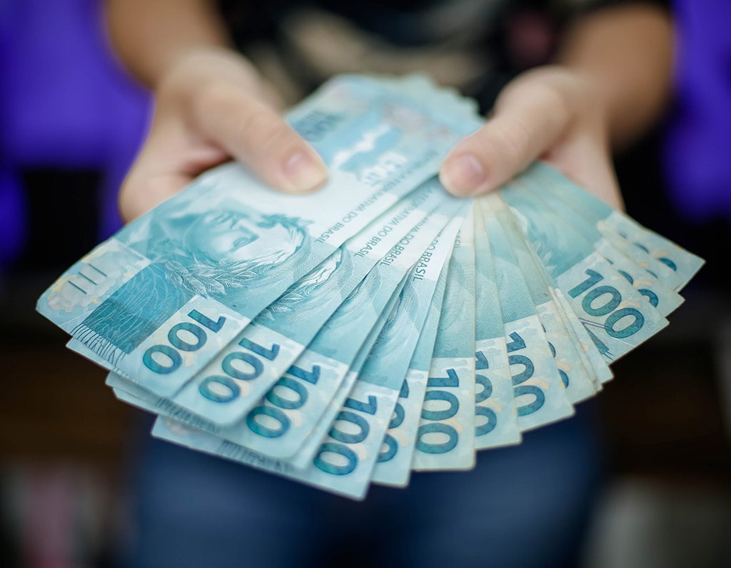 Quanto ganha um Instagrammer? : M&atilde;os segurando v&aacute;rias notas de cem reais