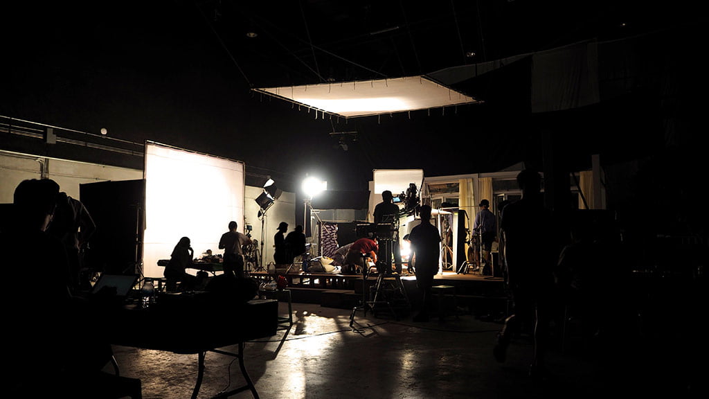 Fa&ccedil;a a cobertura de um evento : silhuetas de equipe de produ&ccedil;&atilde;o os bastidores de um est&uacute;dio fazendo grava&ccedil;&otilde;es de evento