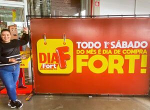 campanha fortatac influencer blogueirafamosa ao lado de uma placa publicitária do fort