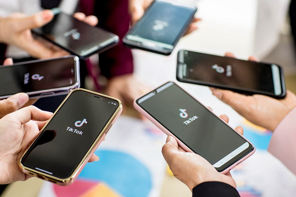 Marketing de influ&ecirc;ncia no TikTok : v&aacute;rias m&atilde;os segurando aparelhos celualres na tela do tiktok