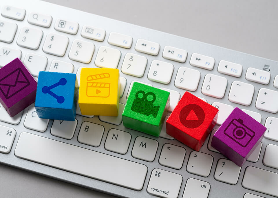 Teclado de computdor branco com vários quadradinhos coloridos e de madeira com ícones de conteúdo digital