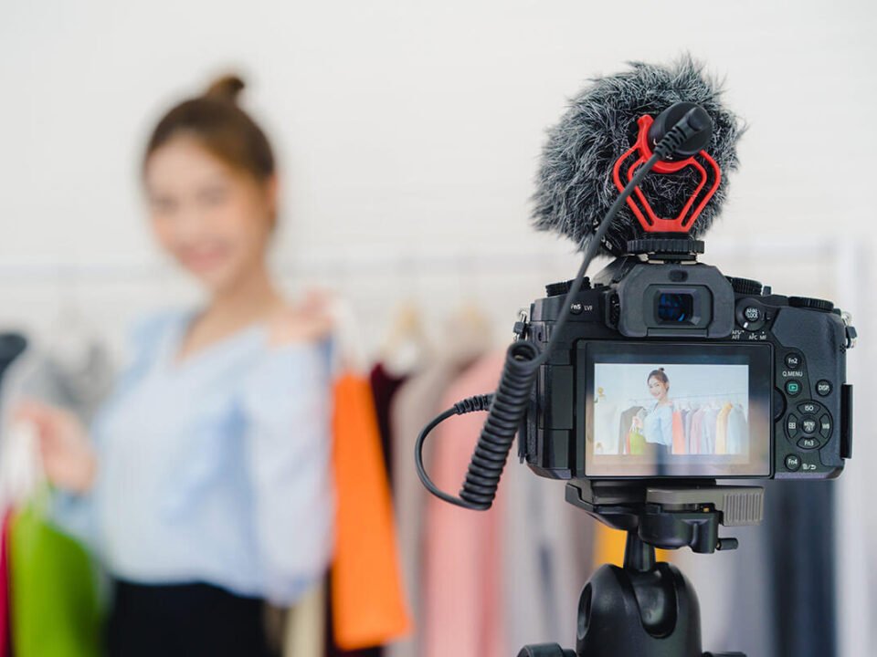 Influencer segurando sacolas coloridas fazendo divulgação em live
