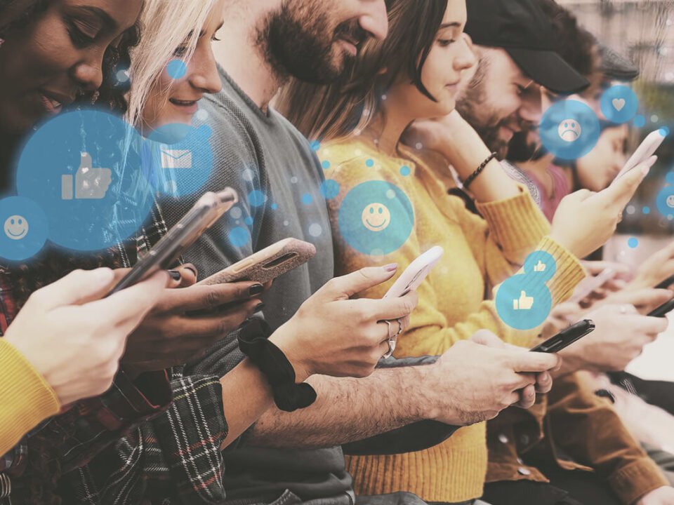 Grupo de pessoas, uma ao lado da outra, utilizando as redes sociais